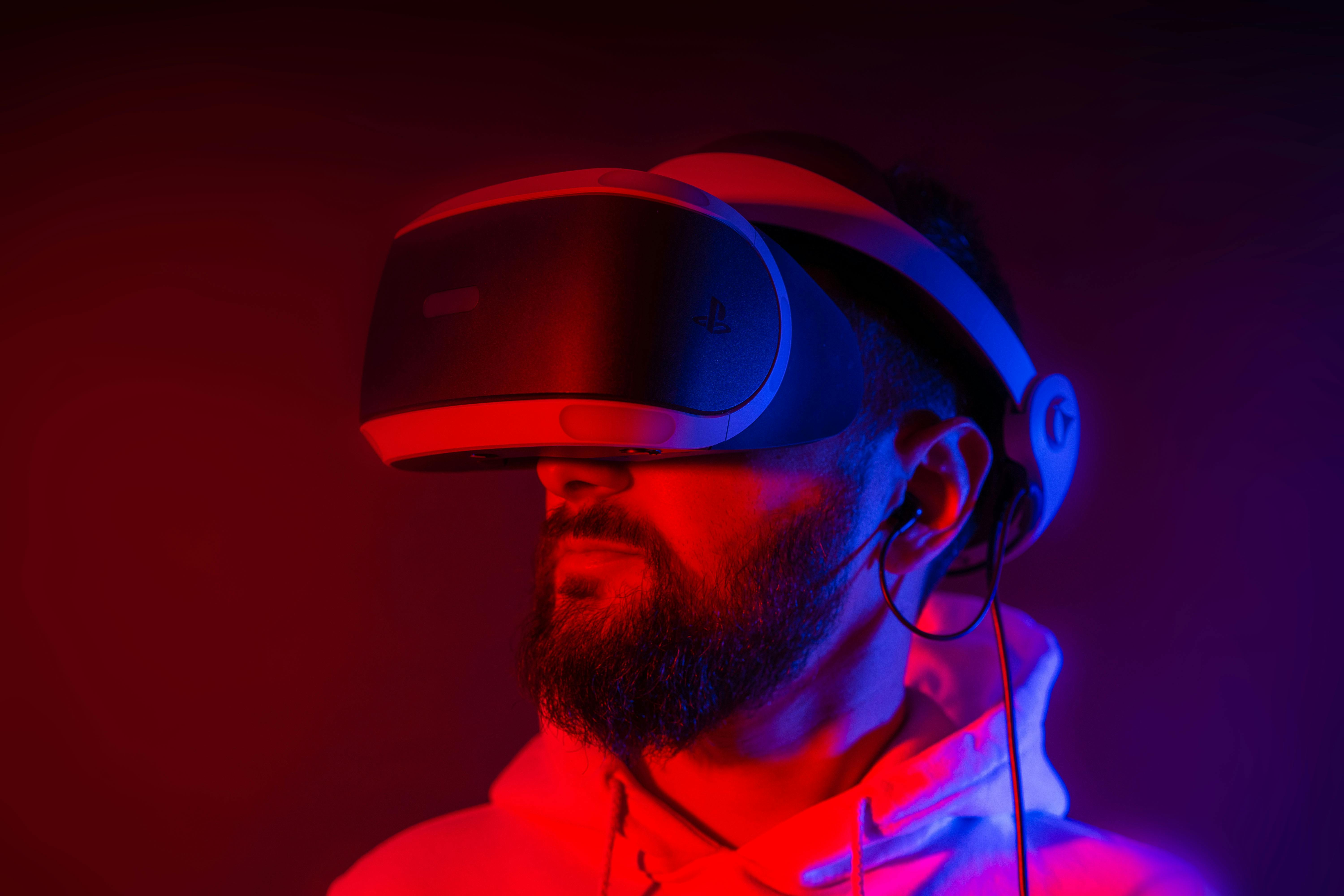 Young bearded man entertaining with VR glasses in colorful neon light on black background